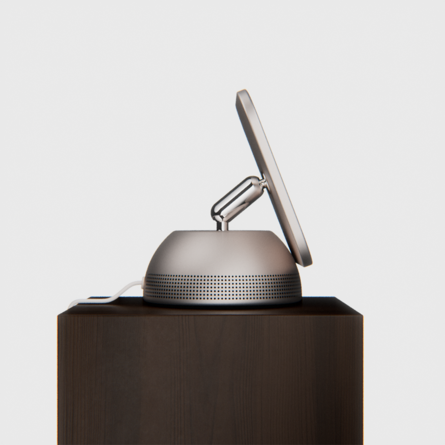 Side view of a slim display on a polished articulated arm and perforated speaker base, set on a wooden pedestal